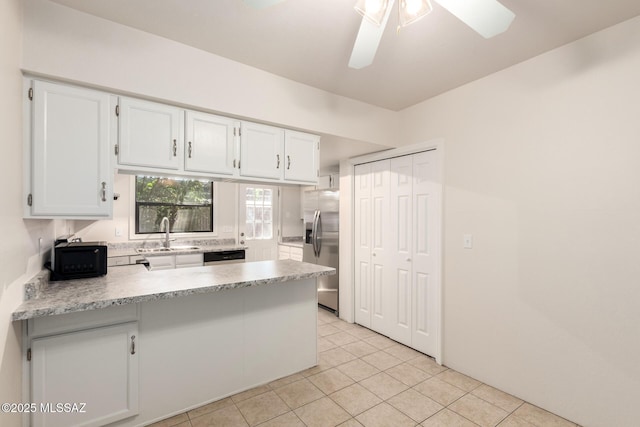 kitchen with appliances with stainless steel finishes, a peninsula, light countertops, white cabinetry, and light tile patterned flooring