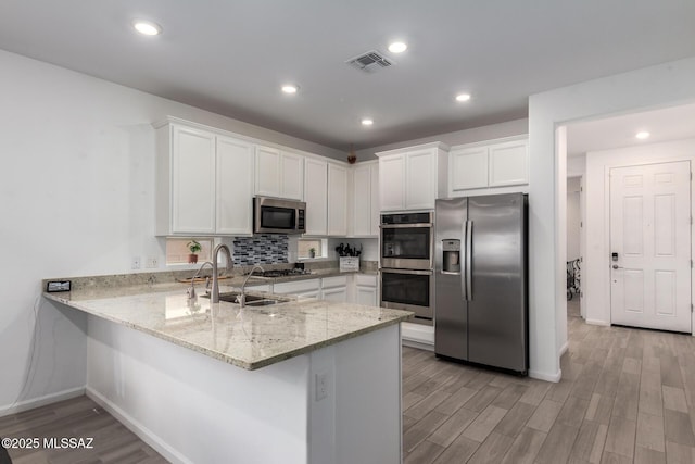 7988 S Bonanza Park Dr, Tucson, AZ 85747 - kitchen with appliances with stainless steel finishes, a sink, a peninsula, white cabinetry, and recessed lighting