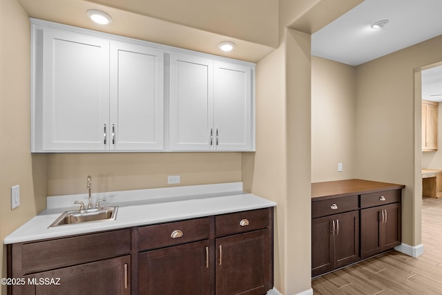 60922 E Arbor Basin Rd, Oracle, AZ 85623 - kitchen with a sink, white cabinetry, light wood finished floors, and dark brown cabinetry