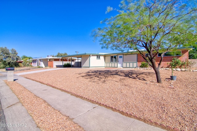 ranch-style home featuring concrete driveway, brick siding, a carport, and fence