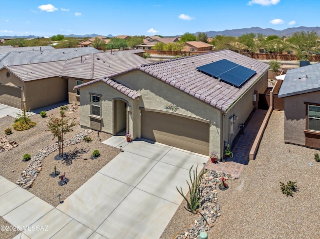 7138 W Ferntree Ln, Tucson, AZ 85757 - view of front facade with stucco siding, solar panels, an attached garage, driveway, and a mountain view