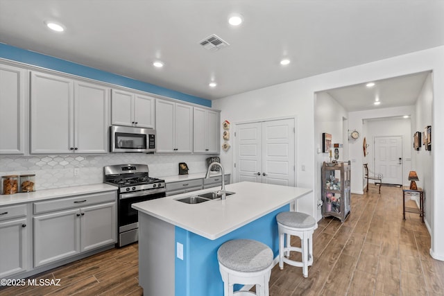 7138 W Ferntree Ln, Tucson, AZ 85757 - kitchen with stainless steel appliances, a sink, dark wood-type flooring, a kitchen bar, and a center island with sink