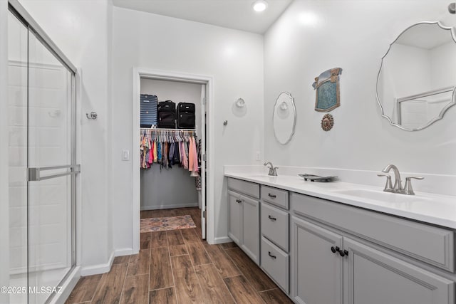 7138 W Ferntree Ln, Tucson, AZ 85757 - bathroom featuring wood finished floors, a shower stall, a spacious closet, double vanity, and baseboards