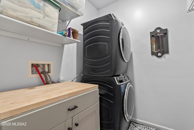 7138 W Ferntree Ln, Tucson, AZ 85757 - laundry area featuring stacked washer and clothes dryer, baseboards, and cabinet space