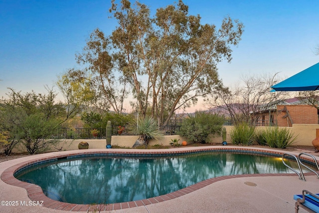 pool at dusk featuring a fenced backyard