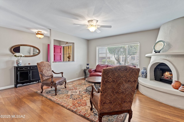 7624 E Helen St, Tucson, AZ 85715 - living area with a lit fireplace, a ceiling fan, wood finished floors, and baseboards
