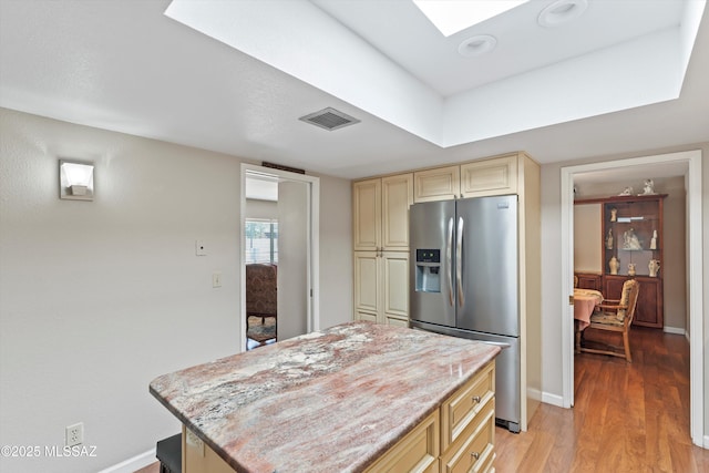 7624 E Helen St, Tucson, AZ 85715 - kitchen with stainless steel fridge with ice dispenser, cream cabinets, baseboards, light wood finished floors, and a skylight