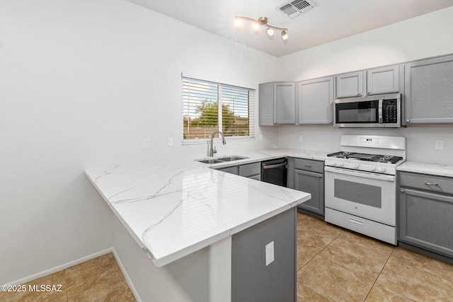 7746 S Trumpet Vine Ave, Tucson, AZ 85747 - kitchen with gray cabinetry, gas range gas stove, stainless steel microwave, a sink, and a peninsula