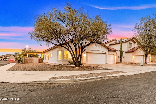 7746 S Trumpet Vine Ave, Tucson, AZ 85747 - view of front of house featuring an attached garage, driveway, stucco siding, and fence