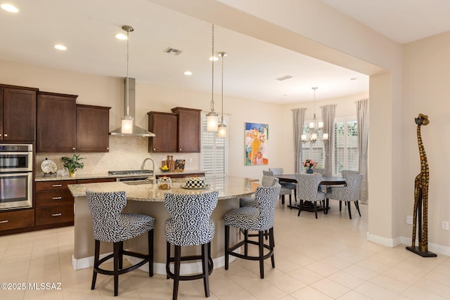 6719 W Kaibab Trl, Marana, AZ 85658 - kitchen featuring wall chimney range hood, double oven, backsplash, a breakfast bar, and recessed lighting