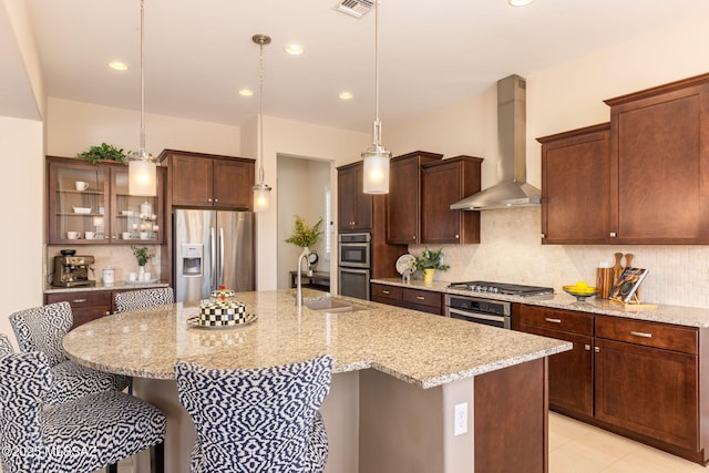 6719 W Kaibab Trl, Marana, AZ 85658 - kitchen featuring wall chimney range hood, appliances with stainless steel finishes, a sink, a breakfast bar area, and a kitchen island with sink
