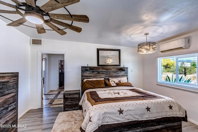 bedroom featuring a wall unit AC, wood finished floors, and baseboards