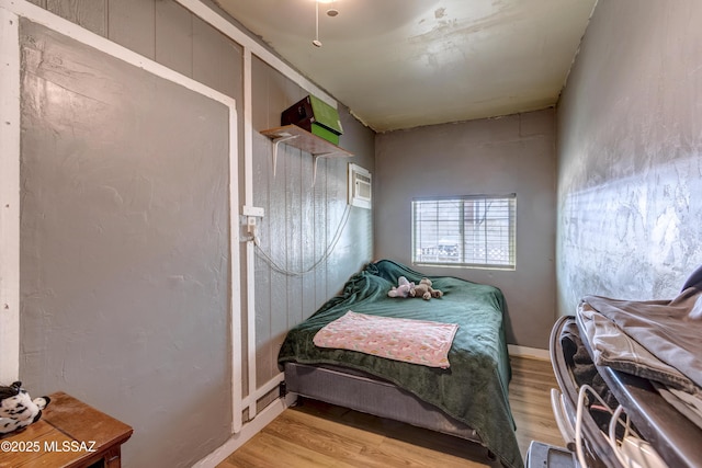 bedroom with light wood finished floors and a wall mounted air conditioner