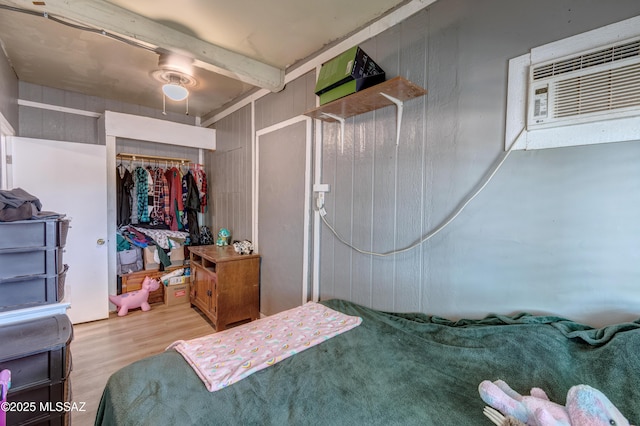 bedroom with wood finished floors, a closet, and an AC wall unit