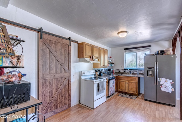 kitchen with stainless steel fridge with ice dispenser, electric range, a barn door, brown cabinetry, and a textured ceiling