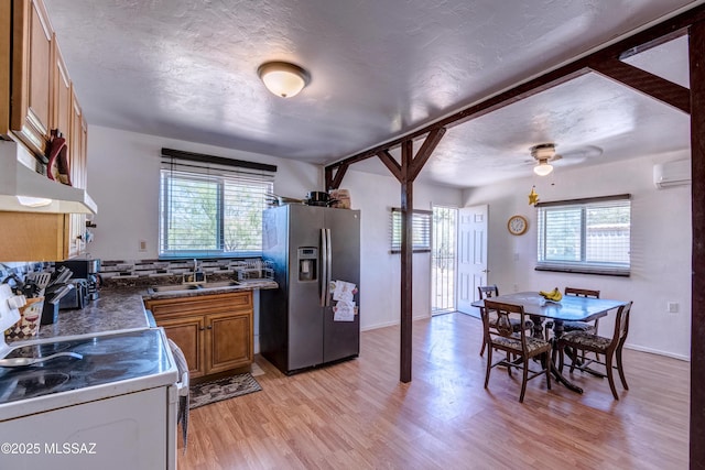 kitchen featuring stainless steel refrigerator with ice dispenser, white electric stove, a sink, brown cabinets, and healthy amount of natural light