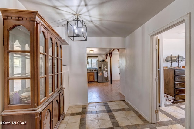 hall featuring a chandelier and baseboards