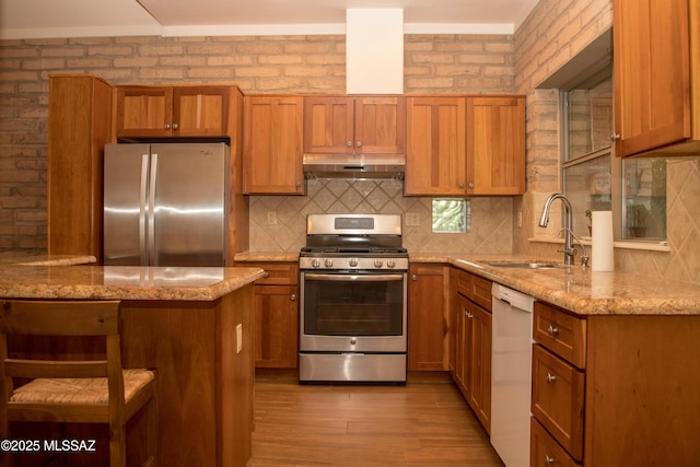 3025 N Gaia Pl, Tucson, AZ 85745 - kitchen featuring appliances with stainless steel finishes, a sink, under cabinet range hood, light wood-style floors, and brown cabinets
