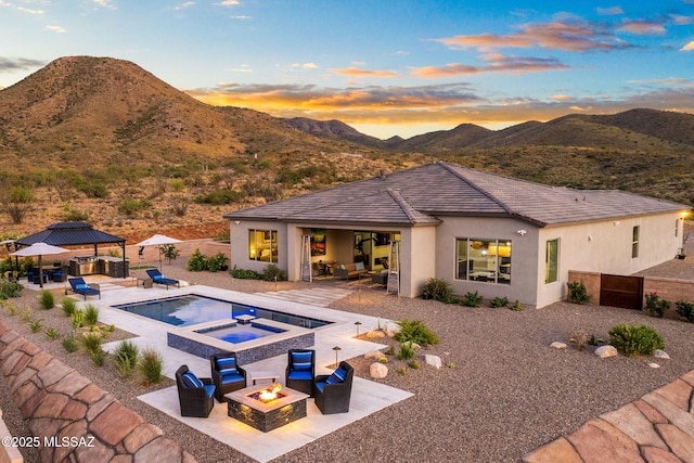 10465 E Ocotillo Rim Trl, Vail, AZ 85641 - back of property at dusk featuring a gazebo, a patio area, a mountain view, and an outdoor living space with a fire pit