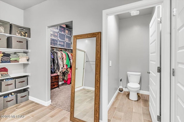 10094 N Cardon Grande Trl, Marana, AZ 85653 - bathroom featuring wood finish floors, a spacious closet, toilet, and baseboards