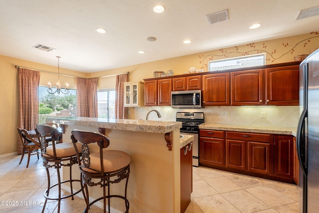 2337 S Via Vespucci, Green Valley, AZ 85614 - kitchen featuring stainless steel appliances, a breakfast bar, a chandelier, a kitchen island, and decorative backsplash