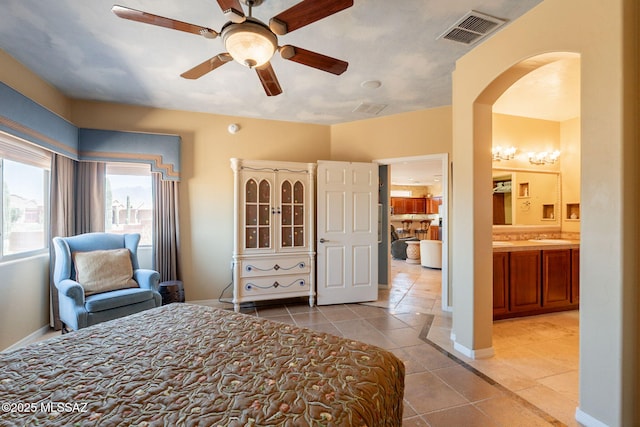 2337 S Via Vespucci, Green Valley, AZ 85614 - bedroom featuring light tile patterned floors, arched walkways, baseboards, a ceiling fan, and connected bathroom