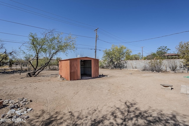 view of yard with a shed, fence, and an outbuilding