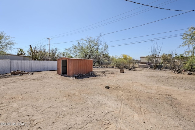view of yard featuring a storage shed, fence, and an outdoor structure