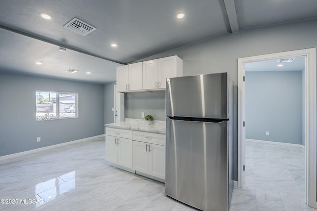 kitchen featuring freestanding refrigerator, light marble finish floors, white cabinets, recessed lighting, and light stone counters