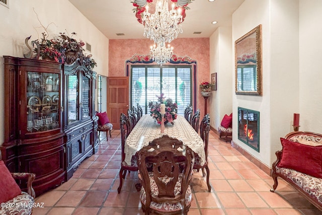 tiled dining area with a chandelier, a glass covered fireplace, and baseboards