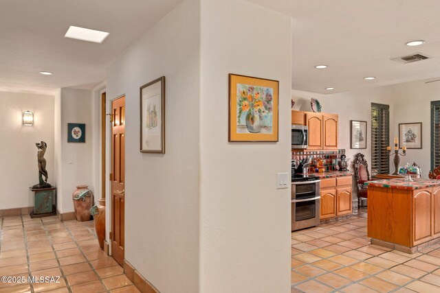 hallway with recessed lighting, light tile patterned floors, and baseboards