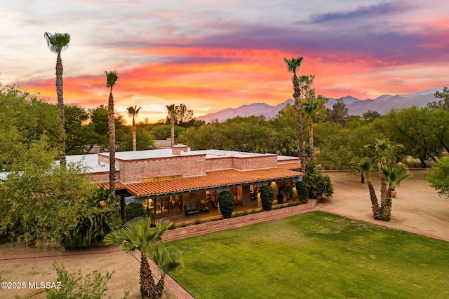 view of front facade featuring a front lawn, a mountain view, and a tile roof