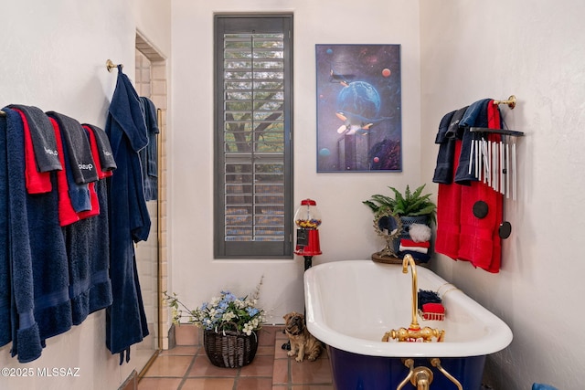 full bath featuring a freestanding tub, tile patterned flooring, and a sink