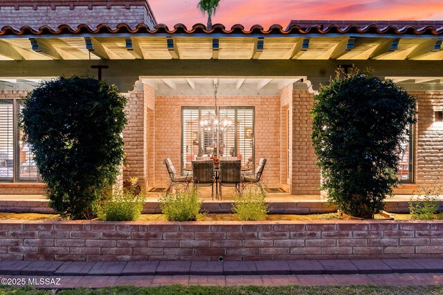 entrance to property featuring a patio and brick siding
