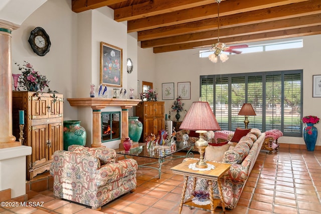 tiled living area featuring beam ceiling, a ceiling fan, decorative columns, and a high ceiling