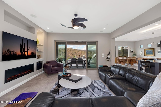 66450 E Sundance Pl, Saddlebrooke, AZ 85739 - living area featuring a ceiling fan, a glass covered fireplace, built in shelves, recessed lighting, and light tile patterned floors
