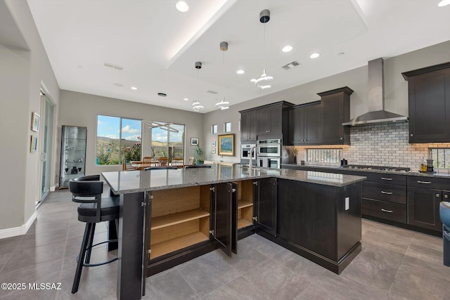 66450 E Sundance Pl, Saddlebrooke, AZ 85739 - kitchen with wall chimney range hood, open shelves, tasteful backsplash, a large island with sink, and stainless steel appliances