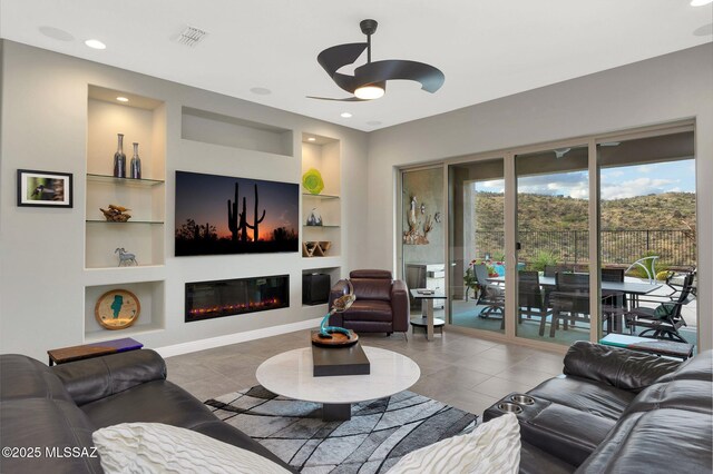66450 E Sundance Pl, Saddlebrooke, AZ 85739 - tiled living room with built in shelves, a ceiling fan, a glass covered fireplace, and recessed lighting