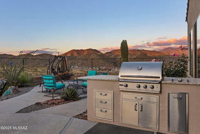 66450 E Sundance Pl, Saddlebrooke, AZ 85739 - patio terrace at dusk with area for grilling, fence, and a mountain view