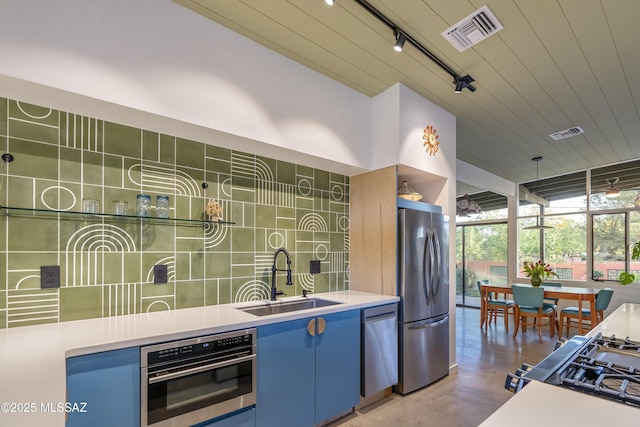 6714 E Topke St, Tucson, AZ 85715 - kitchen with stainless steel appliances, a sink, blue cabinetry, decorative backsplash, and concrete floors