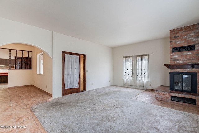 3531 W Goret Rd, Tucson, AZ 85745 - unfurnished living room with a brick fireplace, tile patterned floors, arched walkways, and carpet floors