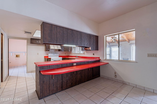 3531 W Goret Rd, Tucson, AZ 85745 - kitchen with electric range, a sink, under cabinet range hood, light tile patterned floors, and dark brown cabinetry