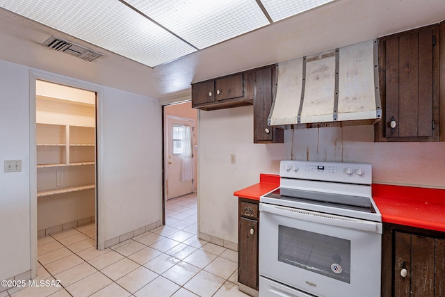 3531 W Goret Rd, Tucson, AZ 85745 - kitchen with white electric range, dark brown cabinetry, ventilation hood, light tile patterned floors, and light countertops