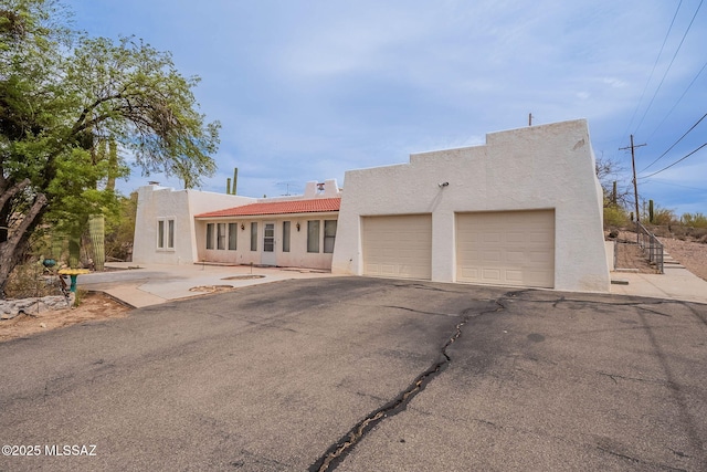 3531 W Goret Rd, Tucson, AZ 85745 - adobe home featuring stucco siding, a garage, asphalt driveway, and a tiled roof
