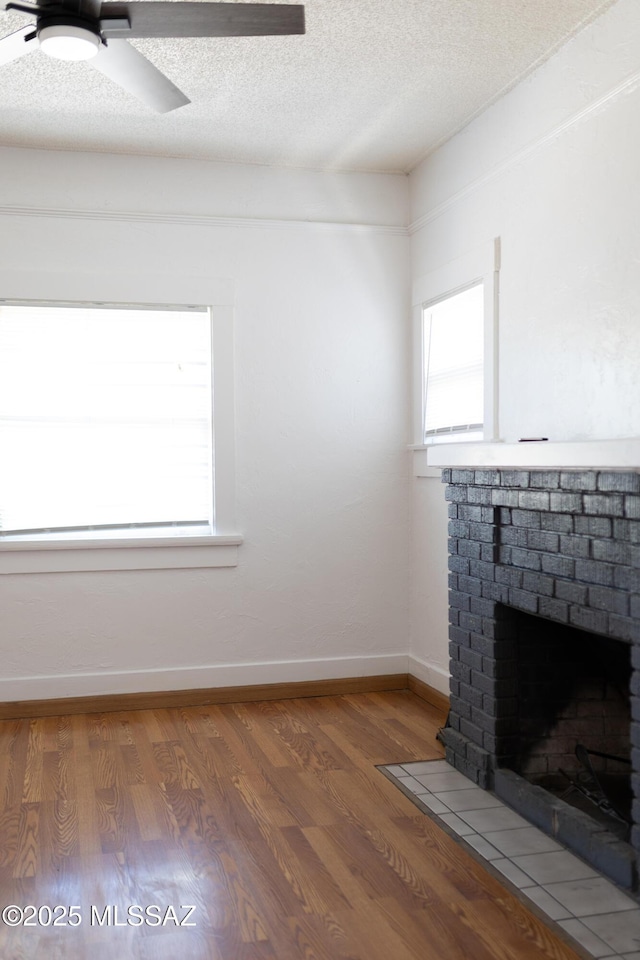616 E 8th St, Tucson, AZ 85705 - unfurnished living room featuring a brick fireplace, a textured ceiling, light wood-style flooring, ceiling fan, and baseboards