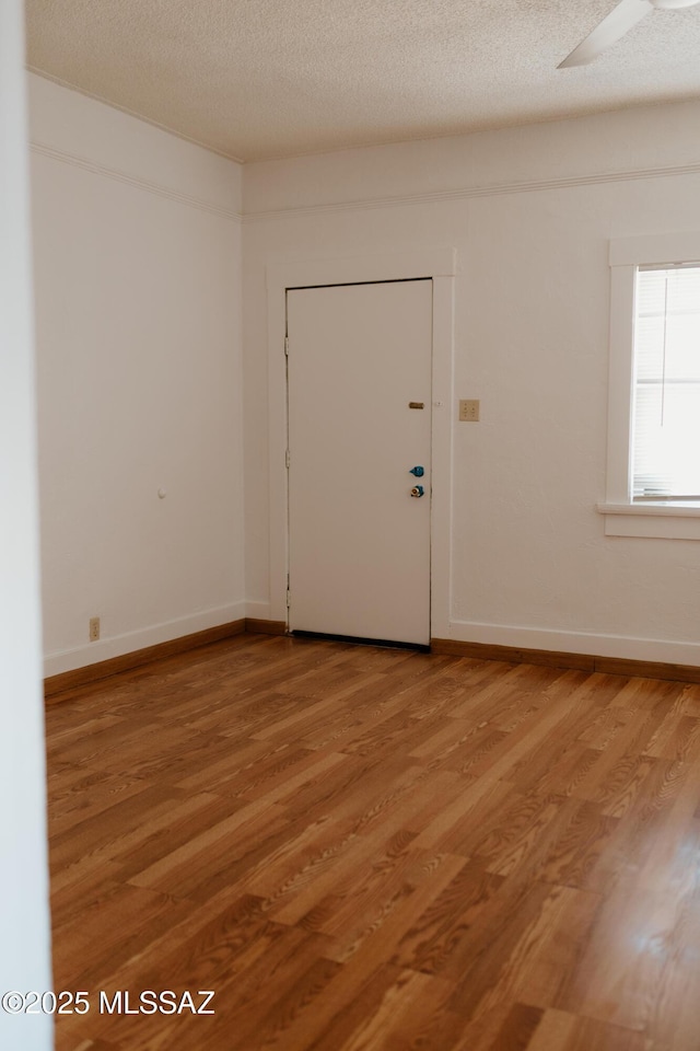 616 E 8th St, Tucson, AZ 85705 - unfurnished room featuring light wood-style flooring, baseboards, and a textured ceiling