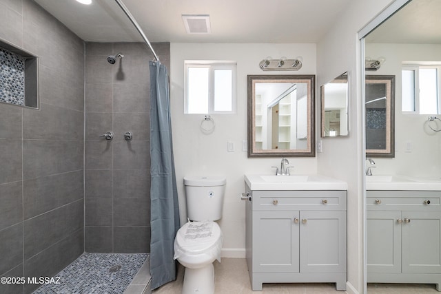 bathroom with a tile shower, plenty of natural light, and toilet