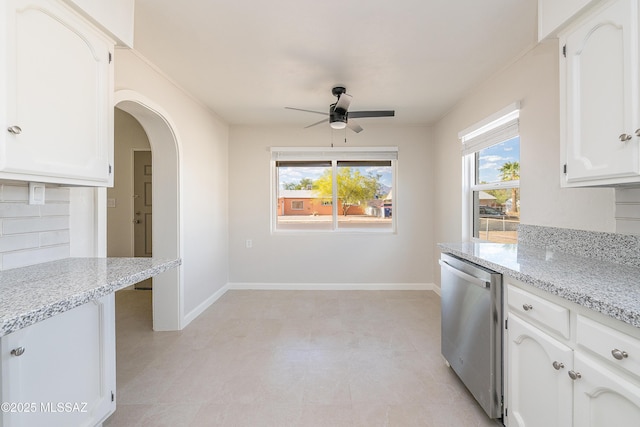 kitchen featuring dishwasher, a ceiling fan, arched walkways, white cabinetry, and light stone countertops