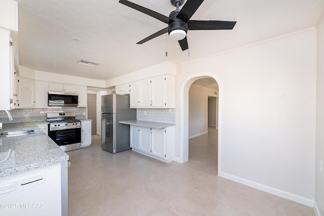 kitchen with stainless steel appliances, a sink, a ceiling fan, backsplash, and arched walkways