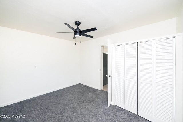 unfurnished bedroom with dark colored carpet, baseboards, a closet, and ceiling fan